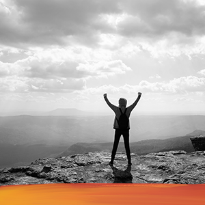 woman COO on mountain top with raised arms
